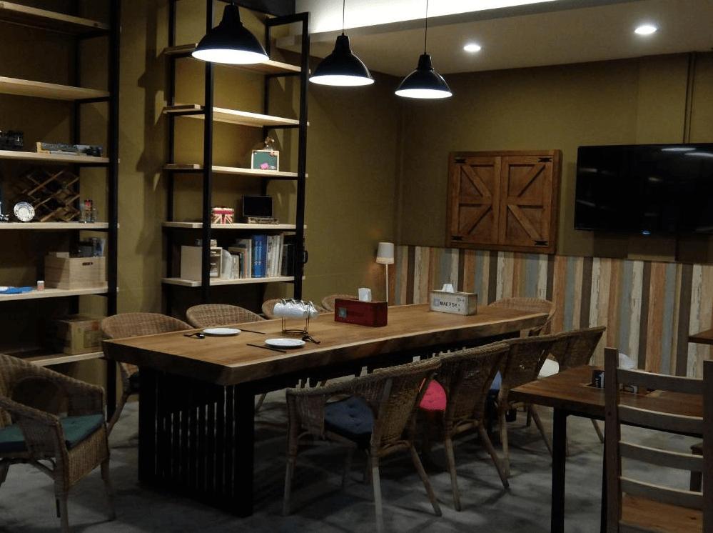 【關山住宿】興源行民宿的公共交誼空間，擺設木質長桌與籐椅，牆面展示層架擺滿書籍與復古小物，空間溫馨，適合閱讀或團體聚會。