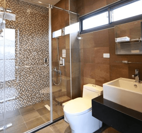 【關山住宿】茶田關舍民宿的浴室空間，設有乾濕分離淋浴間、馬賽克磁磚牆面、現代感洗手台與整潔的馬桶。