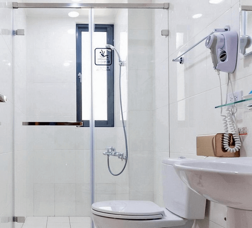 【玉井住宿】藝海民宿的浴室空間整潔明亮，採用白色磁磚設計，配置乾濕分離淋浴間、馬桶、洗手台與吹風機，牆面另設有毛巾架與簡易置物空間，設施齊全、維護良好。