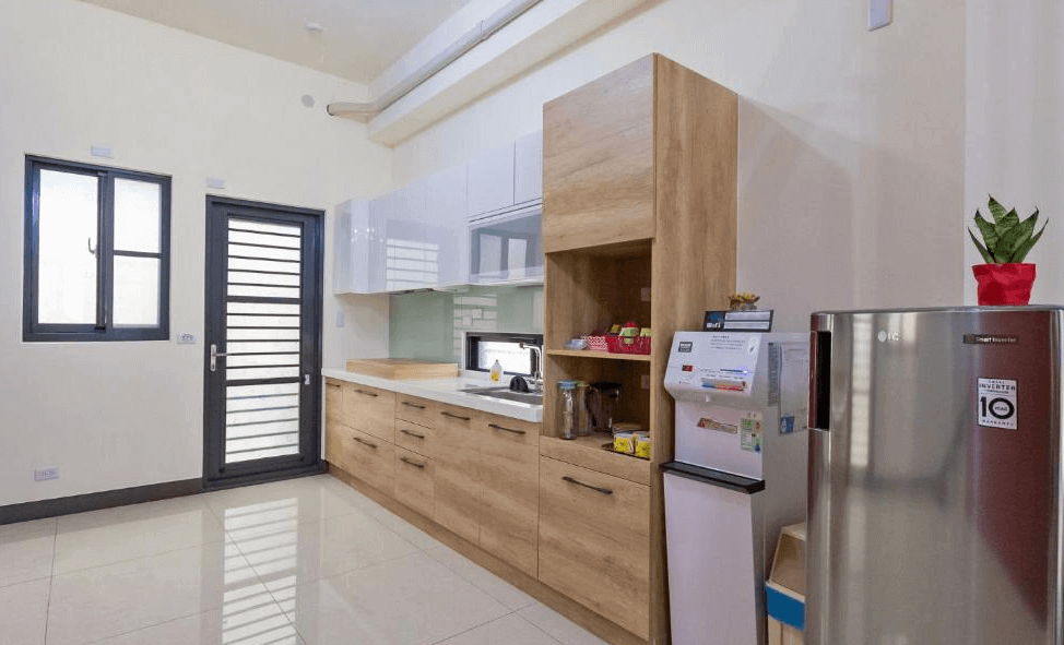 【玉井住宿】藝海民宿的公共廚房空間，配有完整廚具、流理台、冰箱與飲水機，櫃體採用溫潤木紋與白色光面設計，空間整潔寬敞，適合旅客自行簡單料理或沖泡飲品。