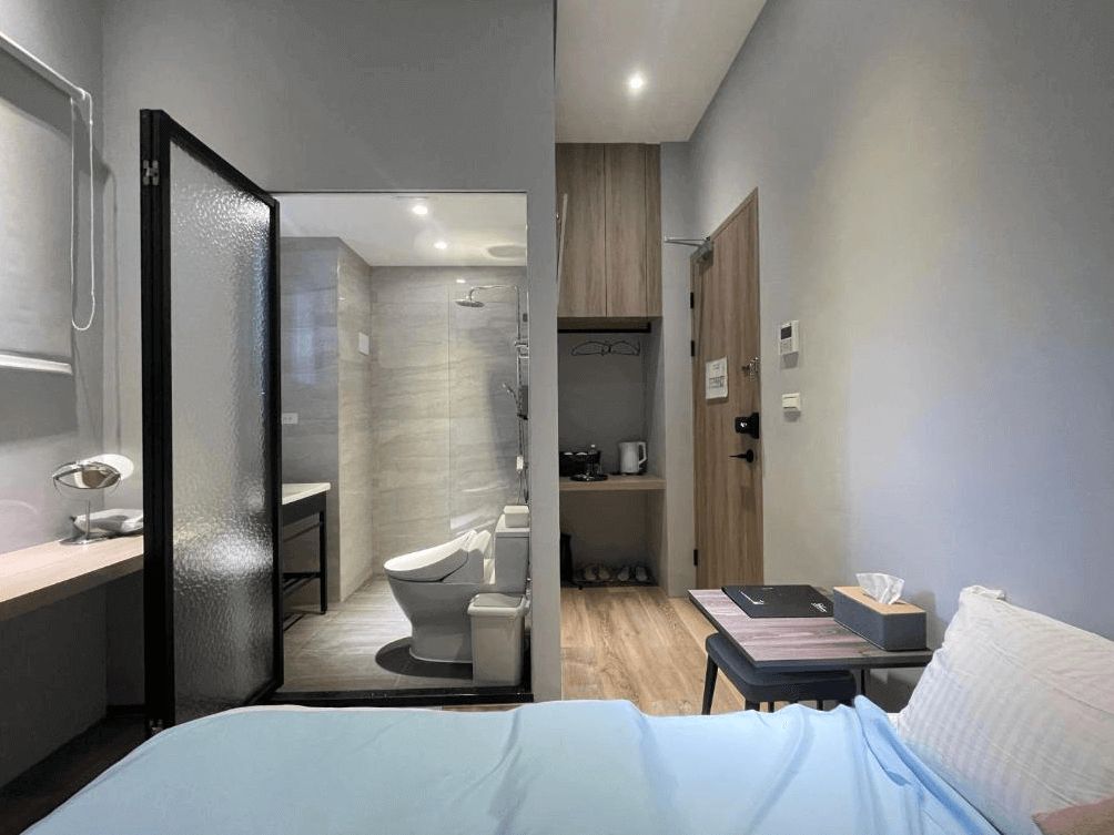 【高雄寵物友善住宿】蘆思特六合民宿的房間內可見獨立衛浴空間，採乾濕分離設計並以透明玻璃門隔開，另有簡易開放式衣櫃與茶水櫃，整體空間機能完善，風格簡潔實用。