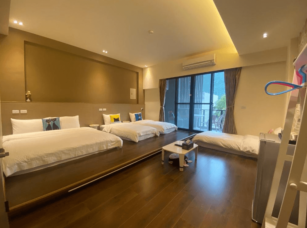 【關山住宿】觀關嚮戶民宿的家庭四人房，配置兩張大床與一張日式床墊，空間寬敞，設有落地窗陽台與山景視野，整體設計溫暖舒適。