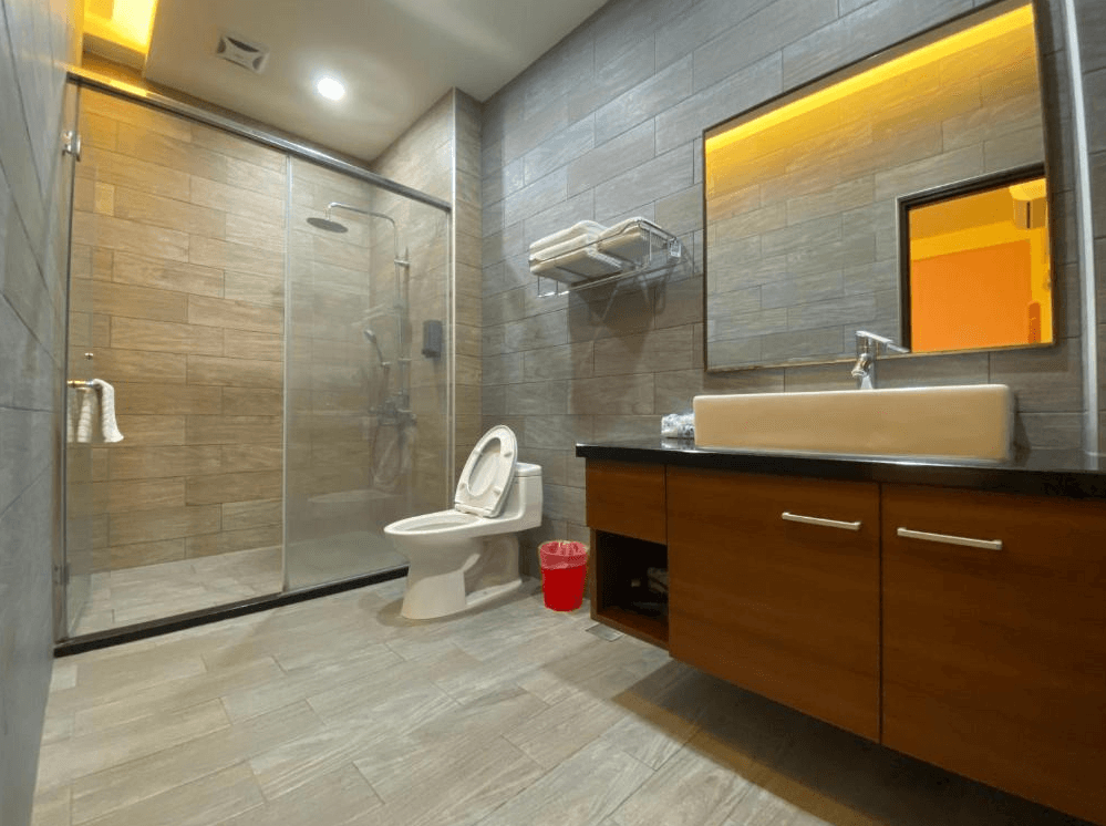 【關山住宿】觀關嚮戶民宿的浴室設計，採乾濕分離規劃，牆面鋪設灰褐色磁磚，設有玻璃拉門淋浴間、現代感洗手台與鏡櫃，整體乾淨整潔。