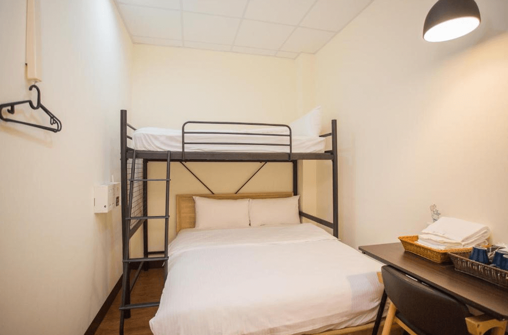 【Xpark住宿】豆子一家輕旅親子房，配置雙人床與上方單人床組成的上下舖，附有簡潔書桌與照明設備，適合一家三口舒適入住。