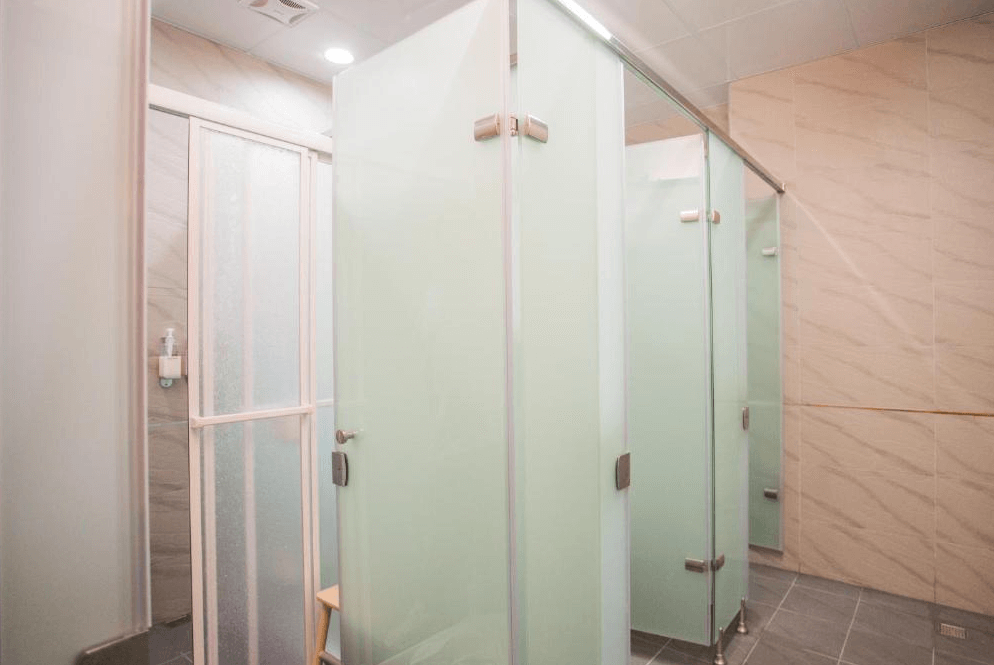 【Xpark住宿】豆子一家輕旅公共淋浴間，設有多間獨立乾濕分離淋浴間與磨砂玻璃門，環境乾淨明亮，提供便利的衛浴設施。
