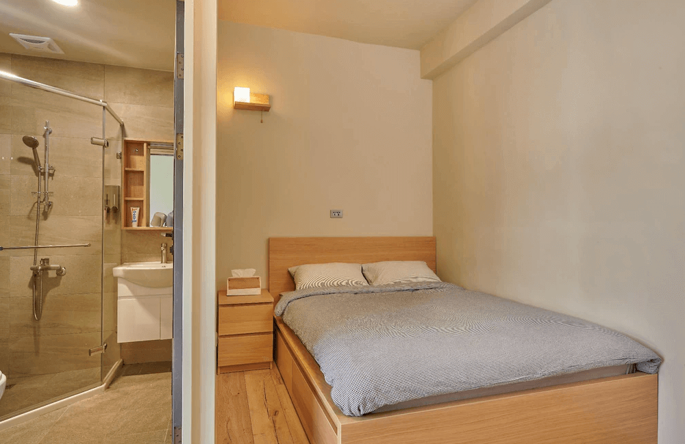 【Xpark住宿】蹤遊三四五雙人房，配有木質雙人床與簡約床頭櫃，衛浴為乾濕分離設計，整體風格溫潤簡潔，適合雙人入住。