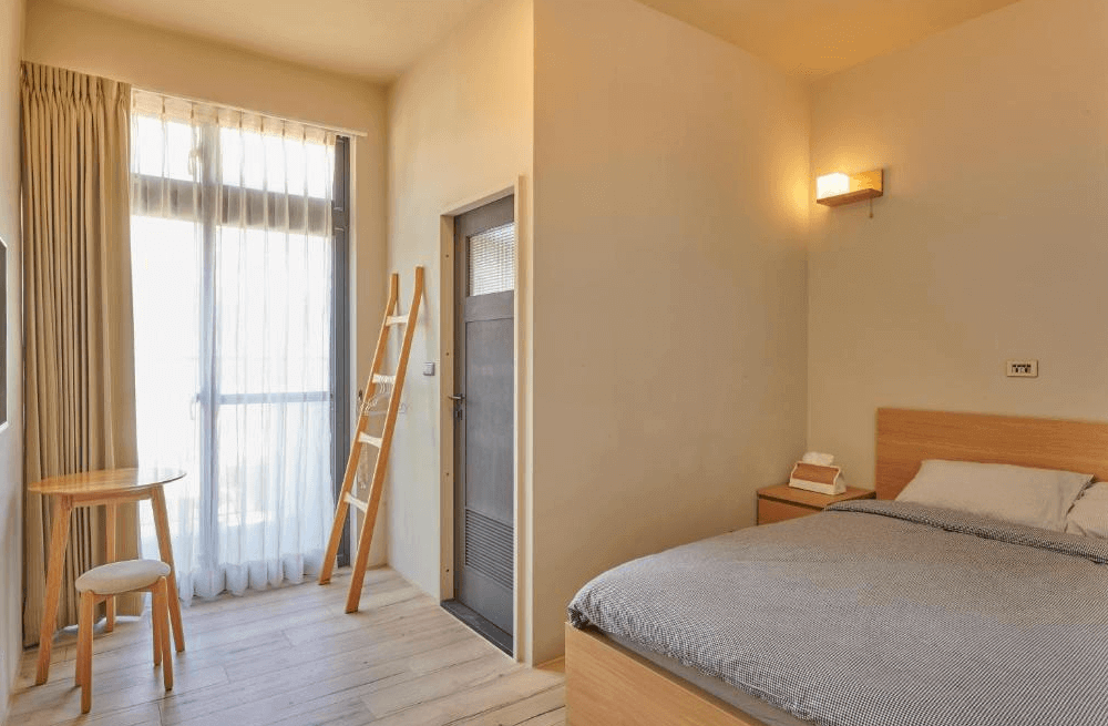 【Xpark住宿】蹤遊三四五自然採光雙人房，房內擺有原木圓桌與高腳椅，大片落地窗引入日光，整體空間清新明亮。