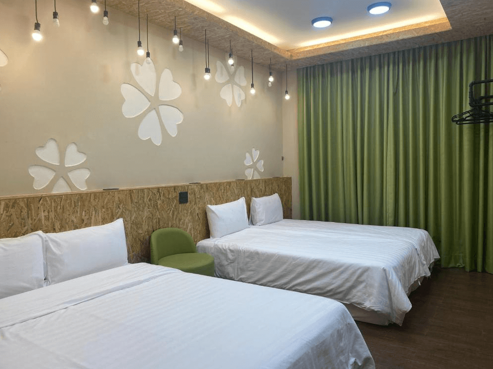 【關山住宿】關山清水莊民宿的雙床主題房型，牆上點綴白色四葉草裝飾，搭配綠色窗簾與木質元素，營造自然又清新的氛圍。