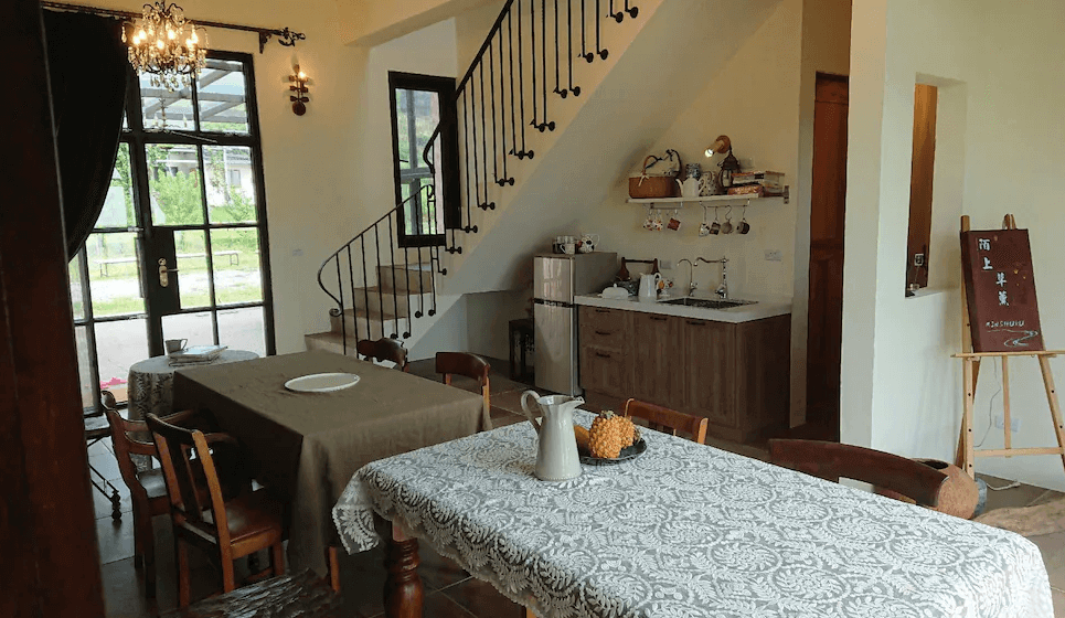 【長濱住宿】陌上草薰民宿公共用餐與廚房區，設有典雅圓桌與木質餐桌，樓梯通往二樓空間，整體布置融合鄉村風格與法式浪漫。