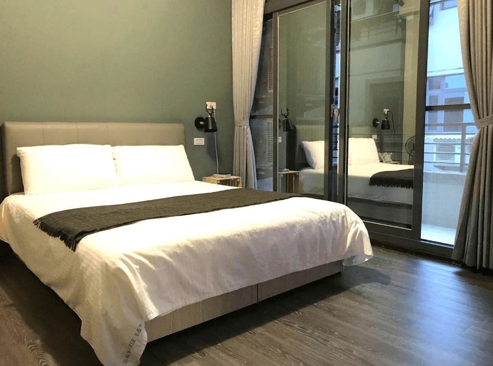 【Xpark住宿】高鐵背包客 HSR B&B 雙人房，設有舒適雙人床與大片玻璃窗，附設獨立陽台空間，房內採用木地板與沉穩色系，營造溫暖氛圍。