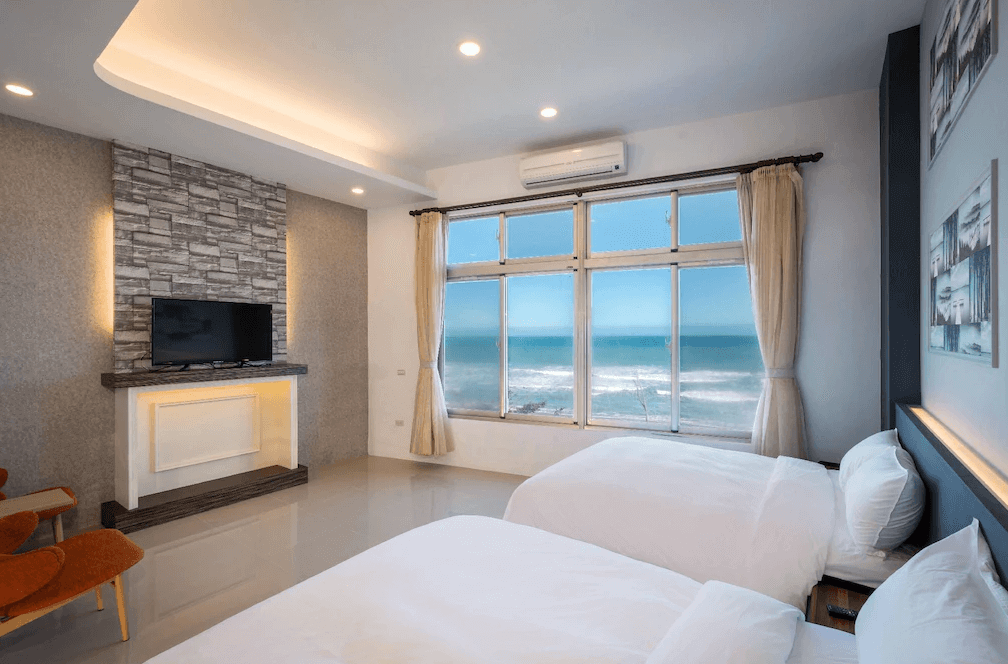 【長濱住宿】默砌旅店東海灣民宿海景雙床房內景，大片落地窗可眺望湛藍海洋，房內配有兩張舒適單人床、平面電視與簡約現代裝潢。