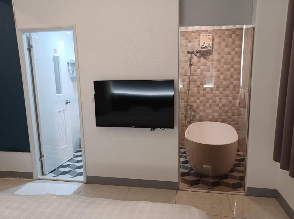 【古坑住宿】111古坑行旅的房型一隅，牆面設有壁掛電視，旁為透明玻璃浴缸空間，兼具開放感與時尚設計，適合年輕旅人或情侶入住。