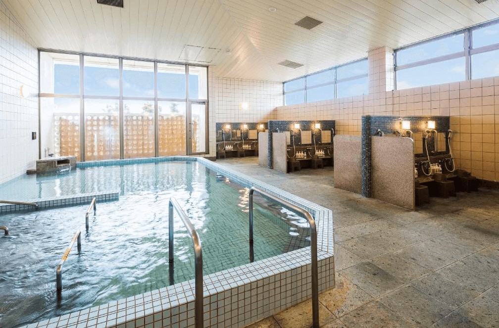 【石垣島住宿】ART石垣島酒店大眾溫泉浴場，寬敞室內空間設有泡湯池與獨立淋浴間，可透過大片窗戶享受自然採光與放鬆時光。