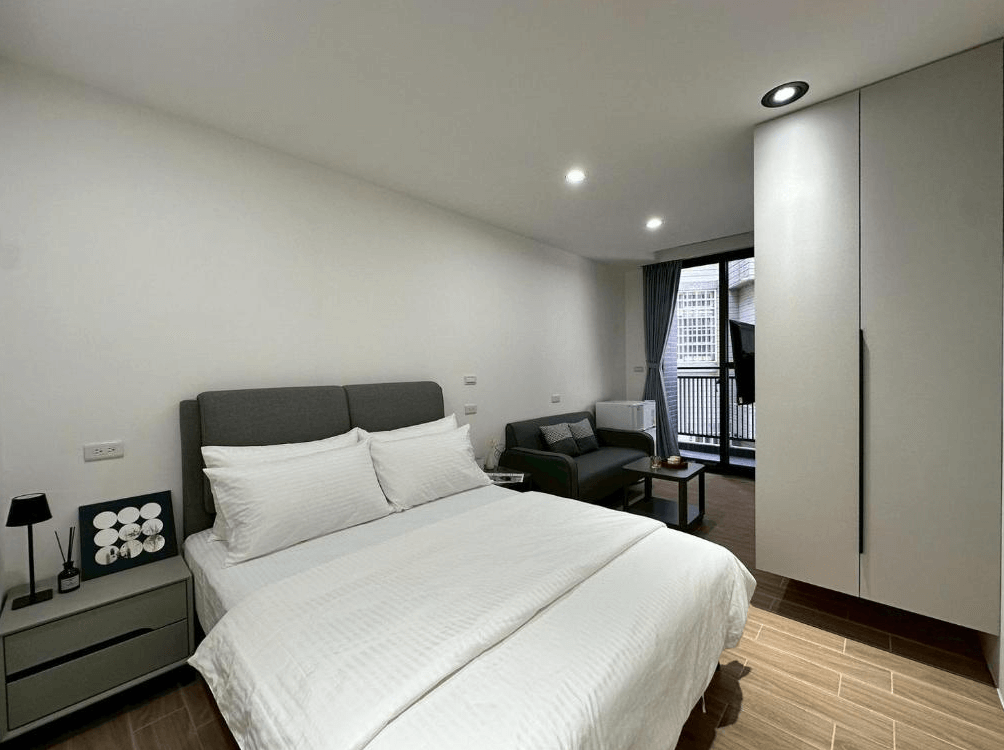 【竹北住宿】NeoStay 新智商旅｜現代風雙人房，配備舒適雙人床、沙發、冰箱與陽台，整體風格沉穩又具質感。