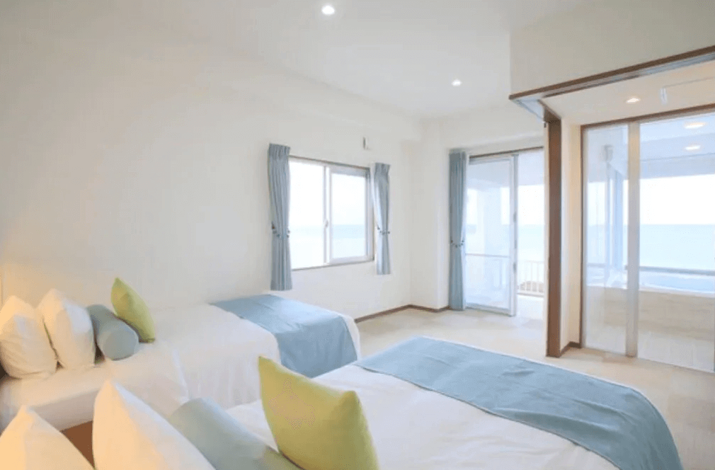 【石垣島住宿】Seven Colors 石垣島海景雙床房，窗外可見大海與陽台景觀，室內設計簡約明亮，適合情侶或家庭入住。