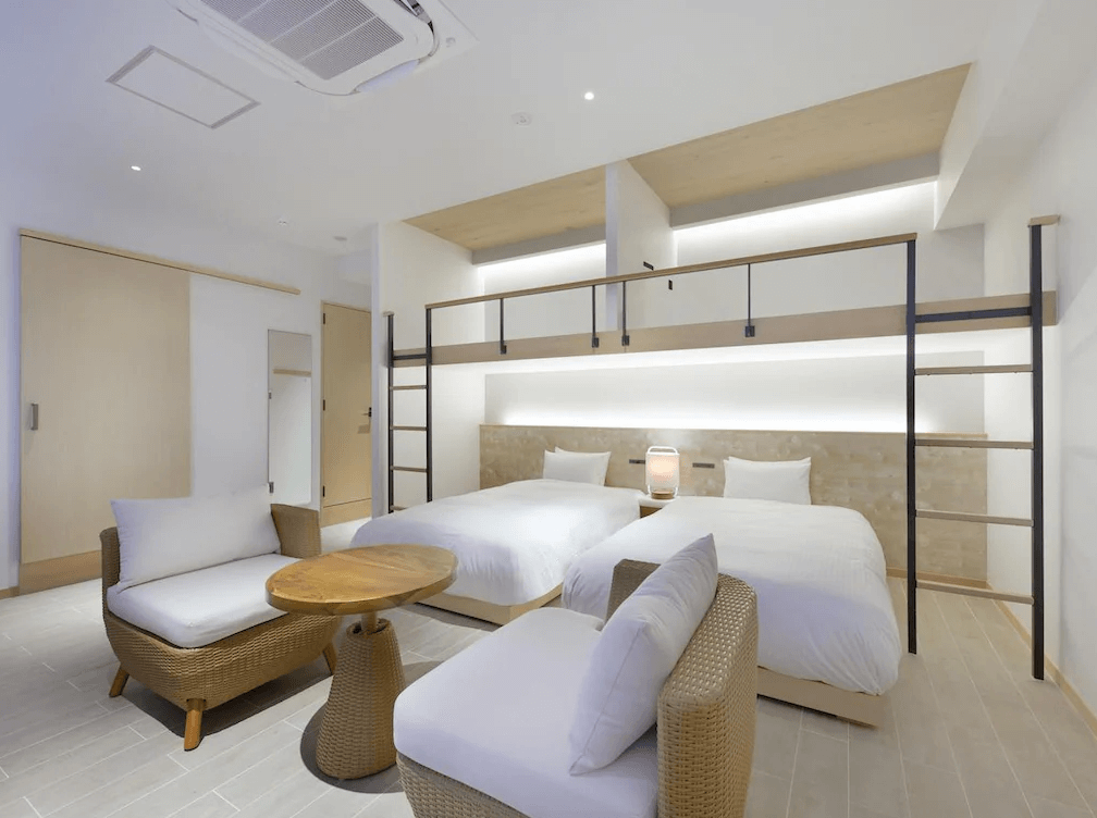 【石垣島住宿】THIRD石垣島四人房，設有上下舖與兩張單人床，搭配藤編沙發與簡約木質家具，室內採光良好，營造出溫馨自然的居住氛圍。