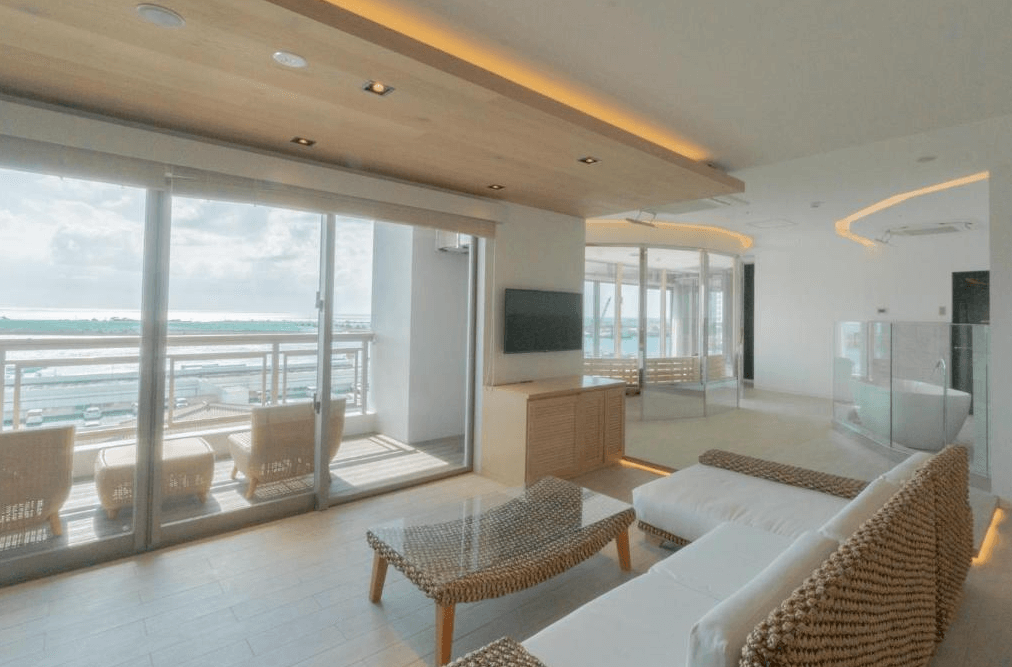 【石垣島住宿】THIRD石垣島頂樓套房客廳空間，大片落地窗可欣賞港灣與海景，搭配現代簡約風格裝潢，空間寬敞舒適，附設半戶外泡湯區。