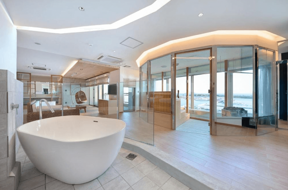 【石垣島住宿】THIRD石垣島頂級套房浴室空間，設有獨立圓形浴缸與大片落地玻璃窗，可遠眺海景，並配備乾濕分離的玻璃蒸氣室，極具現代感。