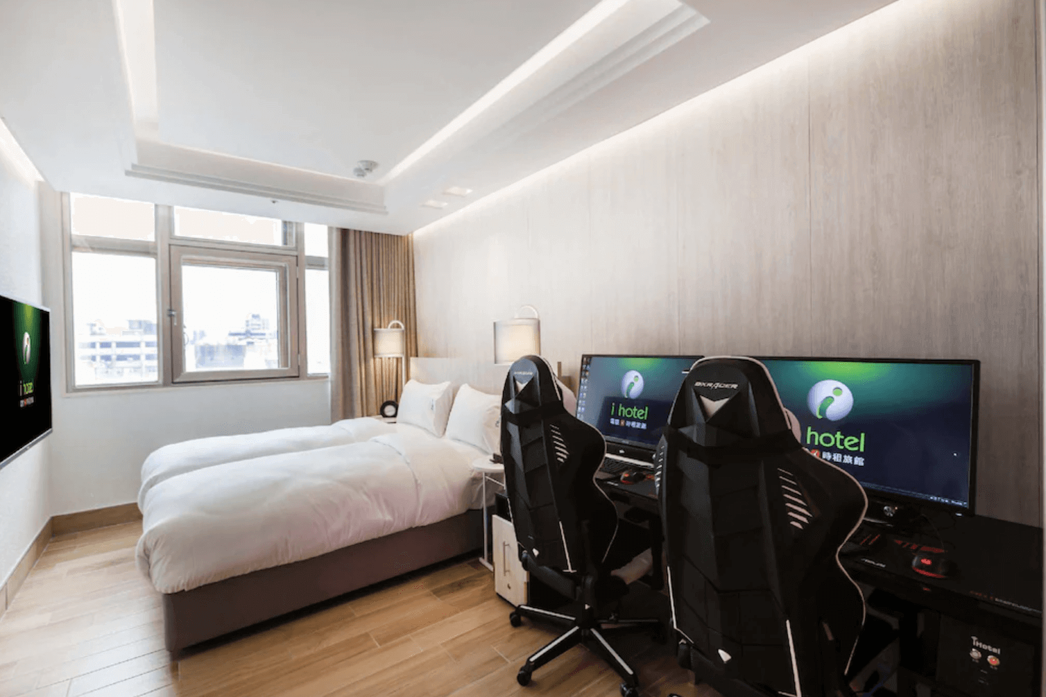 【中壢夜市住宿】i hotel 電競時租旅館的雙人房，配有兩張單人床與兩組高階電競椅與螢幕設備，窗外採光良好，營造舒適明亮的住宿環境。