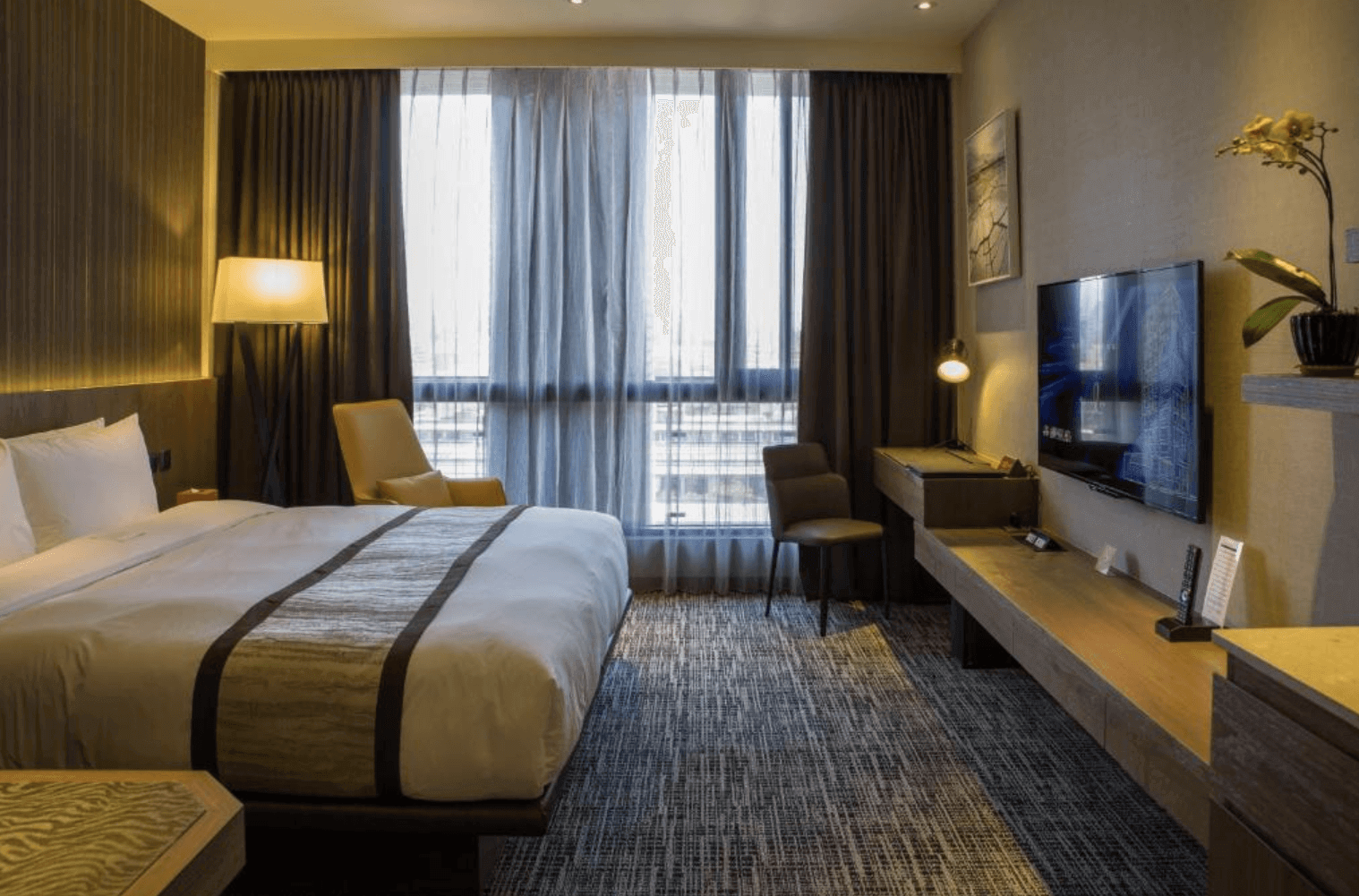 【中壢夜市住宿】三揚精品商旅現代風格的雙人房型，配有舒適大床、大片落地窗與柔和燈光，營造溫馨且具設計感的住宿氛圍。
