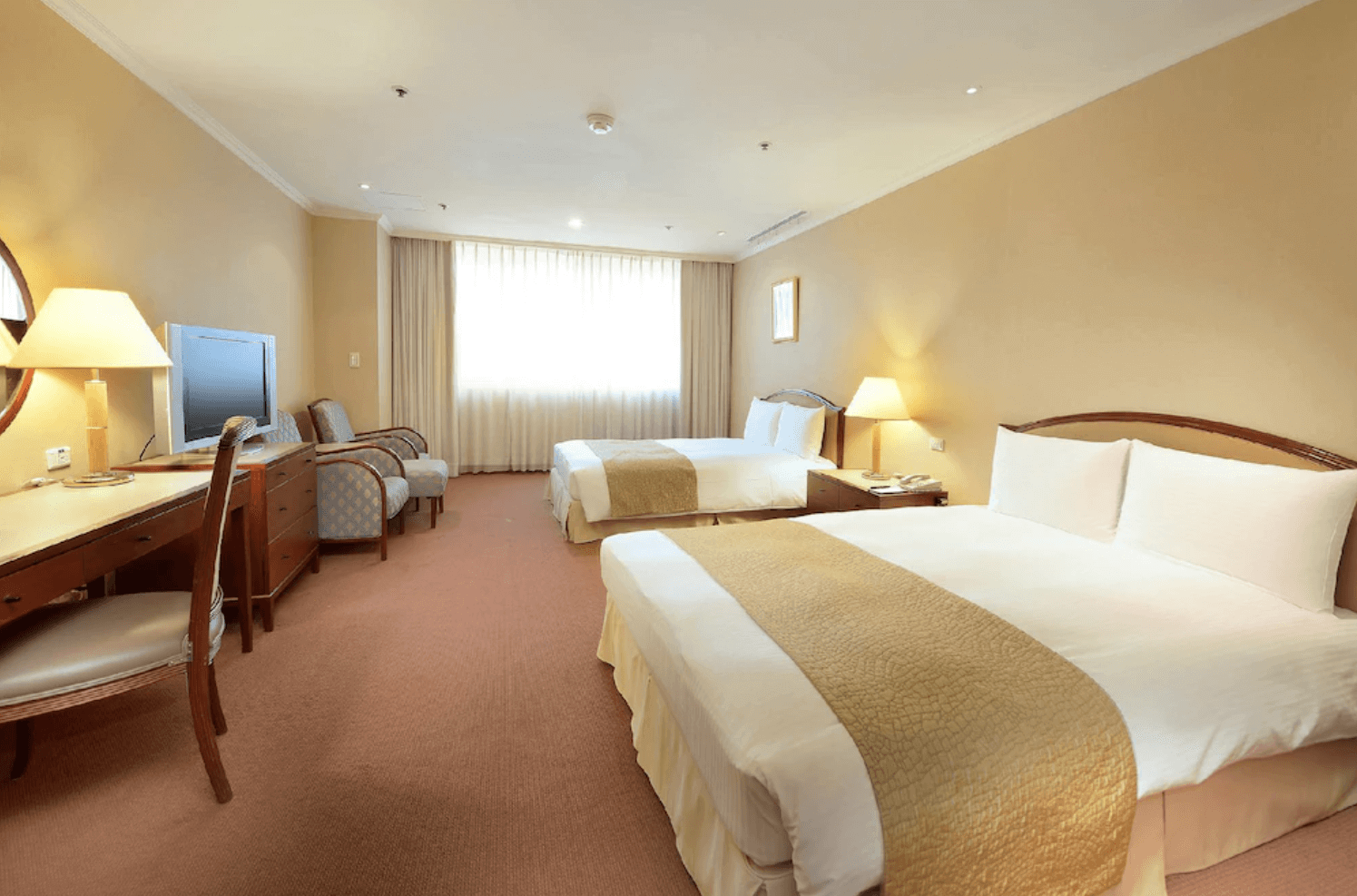 【中壢夜市住宿】中壢米堤大飯店雙床房型，設有兩張大床、書桌與舒適沙發椅，空間寬敞明亮，充滿典雅風格。
