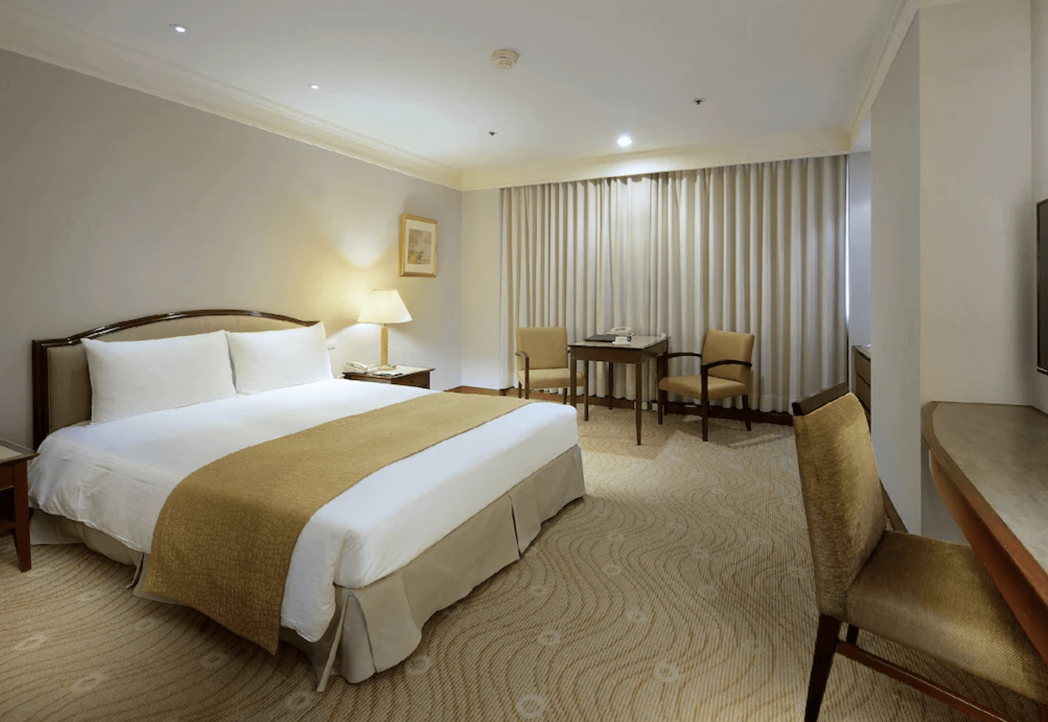 【中壢夜市住宿】中壢米堤大飯店標準雙人房，配有一張特大床、落地窗簾與簡約辦公桌椅，整體設計溫馨沉穩。
