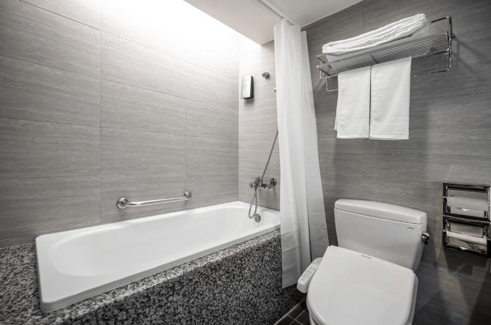 【竹北住宿】享豪大飯店浴室設有傳統浴缸與乾淨的衛浴設備，牆面採用灰色磁磚，提供毛巾與吹風機等基本備品。