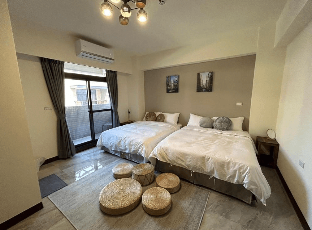 【竹山住宿】伍伍七 Local Supply 四人房型，兩張大床搭配原木色調與簡約風格，地面設有藤編坐墊，展現自然質感與溫馨空間感，適合親子或好友入住。