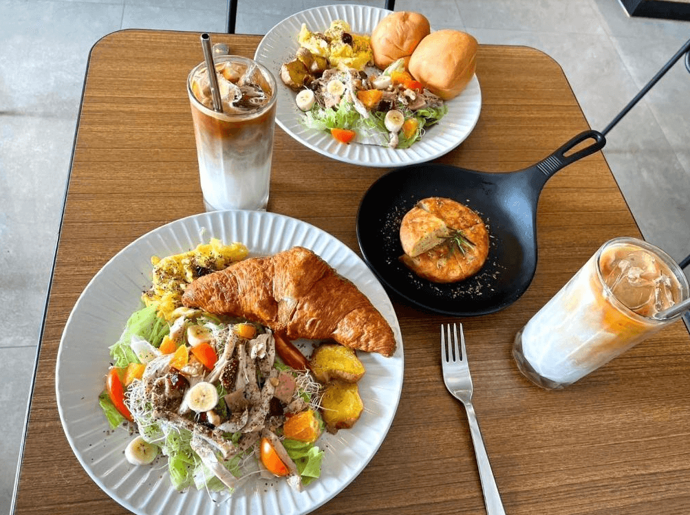 【竹山住宿】伍伍七 Local Supply 招牌早午餐組合，包含可頌沙拉、炒蛋、烤餅與冰拿鐵等豐盛餐點，擺盤精緻，展現高質感的早午餐體驗。