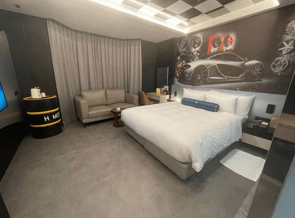 【竹北住宿】佳緹國際精品旅館｜以跑車為主題的設計房型，牆面裝飾醒目吸睛，搭配大床、沙發與工業風擺設，展現獨特個性魅力。