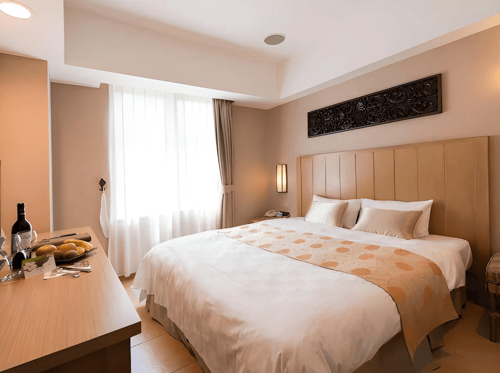 【古坑住宿】劍湖山渡假大飯店的雙人房，設有一張加大雙人床，室內裝潢溫暖舒適，備有迎賓水果與紅酒，適合情侶或夫妻入住。
