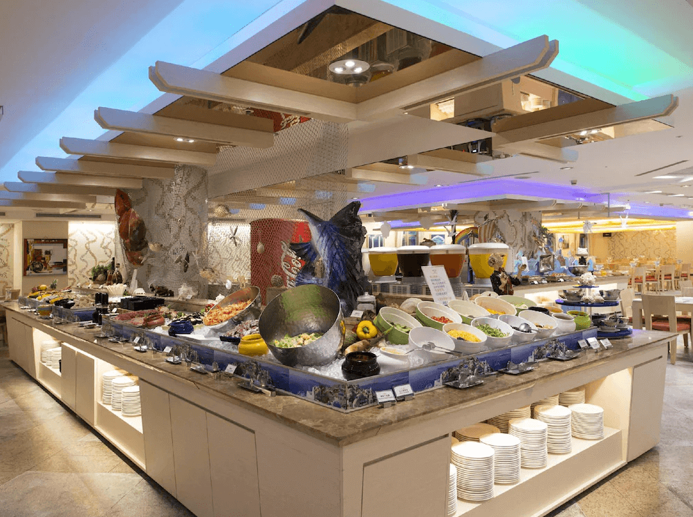 【古坑住宿】劍湖山渡假大飯店的自助餐廳，中央餐檯擺滿各式中西料理、海鮮、沙拉及飲料，環境明亮且裝飾富有海洋風格。