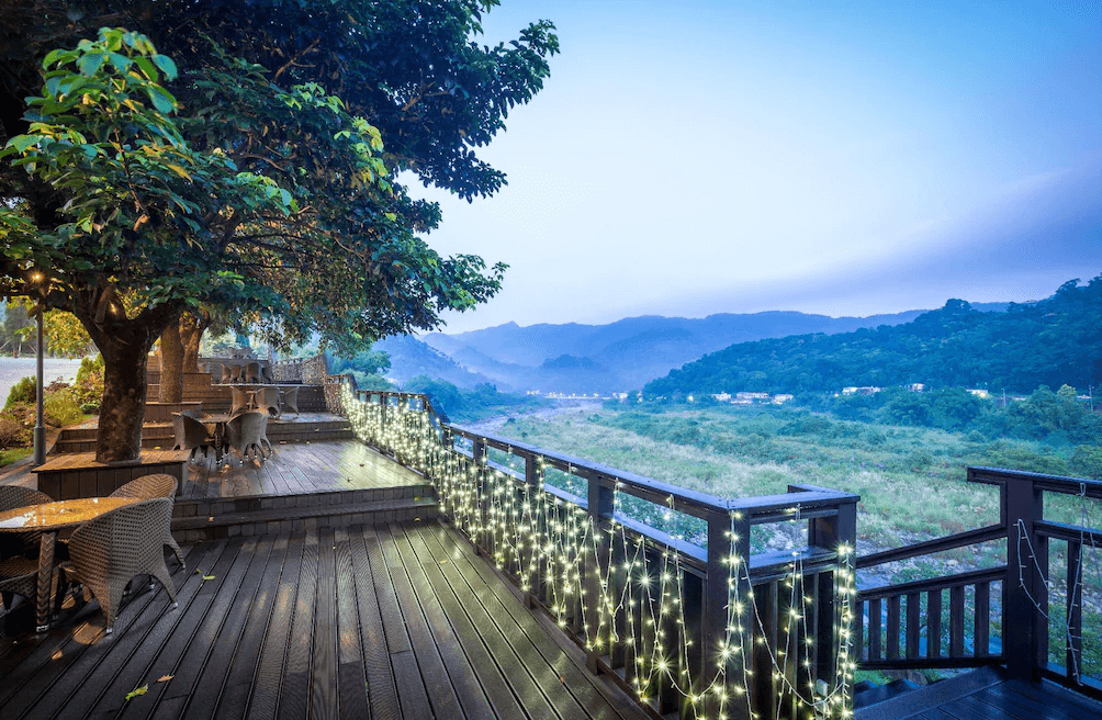【南庄民宿】"南庄民宿精選示意圖"南庄雲水度假溫泉－景觀露天座位區眺望山巒與溪谷，美景搭配燈飾營造夢幻氛圍