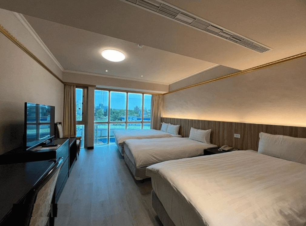 【新竹東區住宿】大道城飯店四人房，設有兩張大床，大片落地窗採光明亮，室內裝潢簡約溫馨，附設電視與書桌。