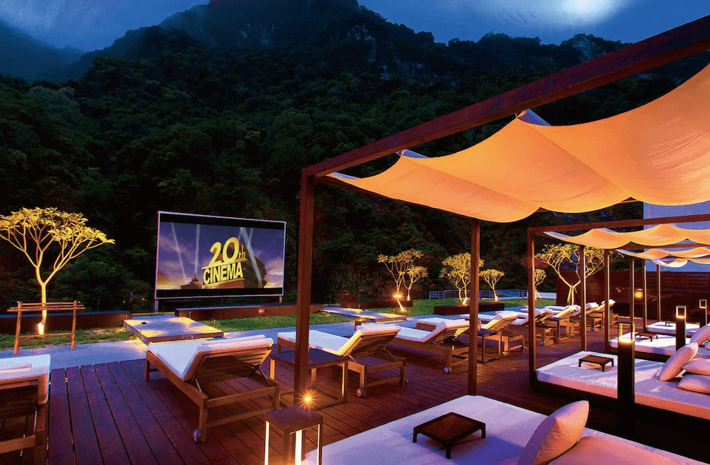 【花蓮寵物友善飯店】太魯閣晶英酒店夜間星空電影院，設有舒適躺椅與遮陽棚，戶外大螢幕播放電影，背景為群山環繞，打造沉浸式的峽谷觀影體驗。