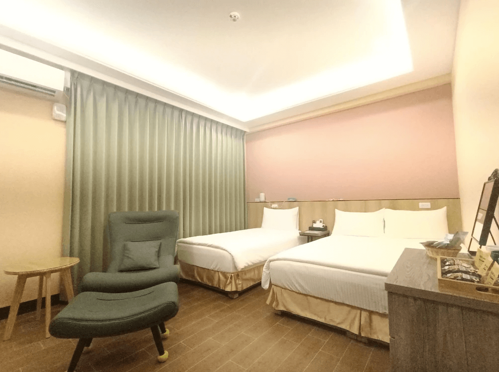 【竹山住宿】怡然自得民宿溫馨雙床房型，粉橘與米色牆面搭配柔和燈光，設有兩張雙人床與休閒躺椅，氛圍溫暖放鬆，適合家庭入住。