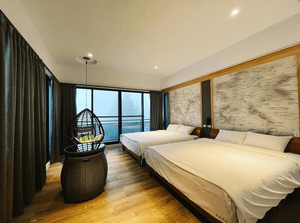 【古坑住宿】意境森林民宿的景觀四人房，設有兩張大床與吊籃椅，大片落地窗外可眺望山林雲霧，室內以木地板與沉穩色調打造自然休閒氛圍。