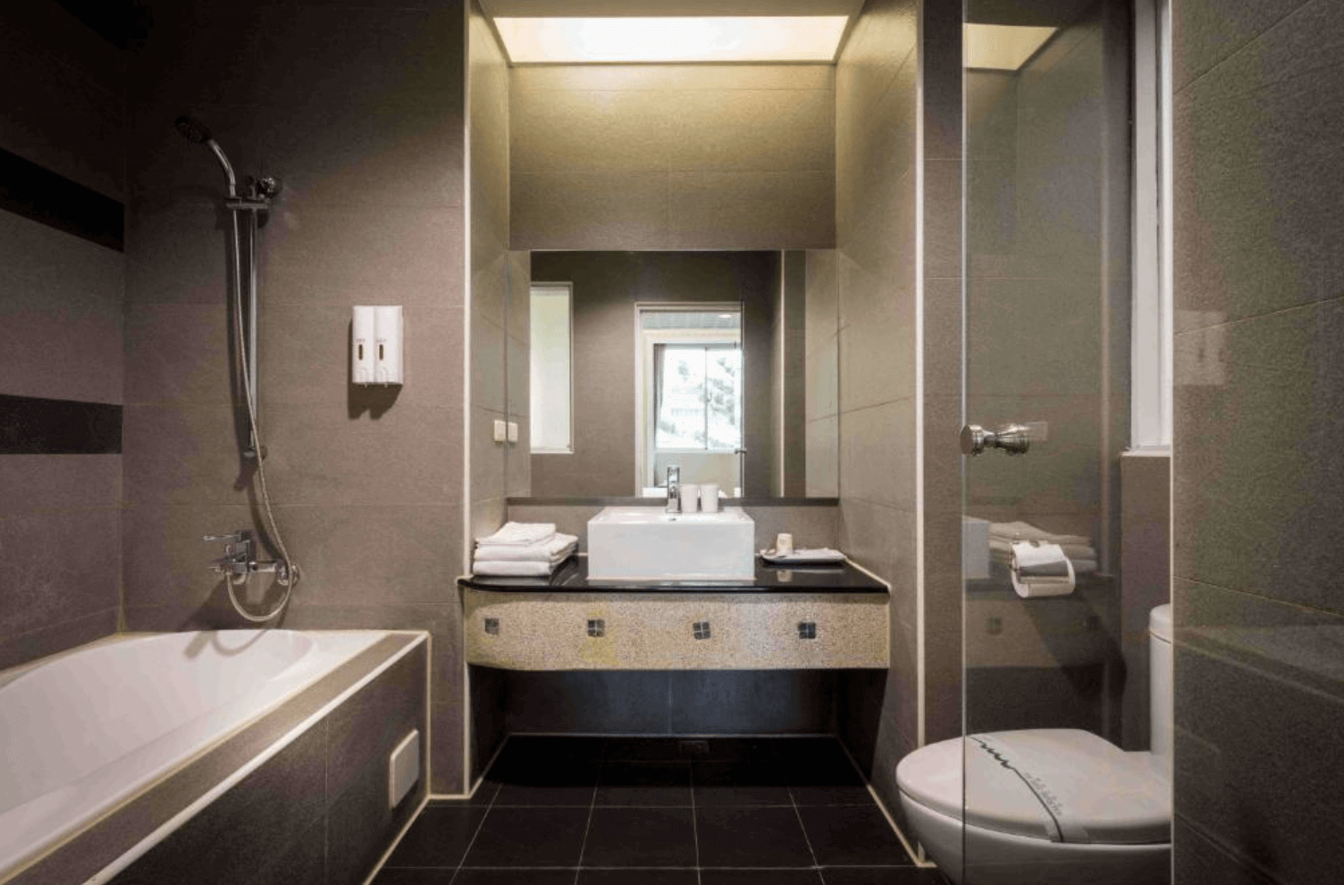 【清水住宿】愛力根汽車旅館灰色調衛浴空間，設有獨立浴缸、乾濕分離淋浴間與現代洗手台，簡約時尚。