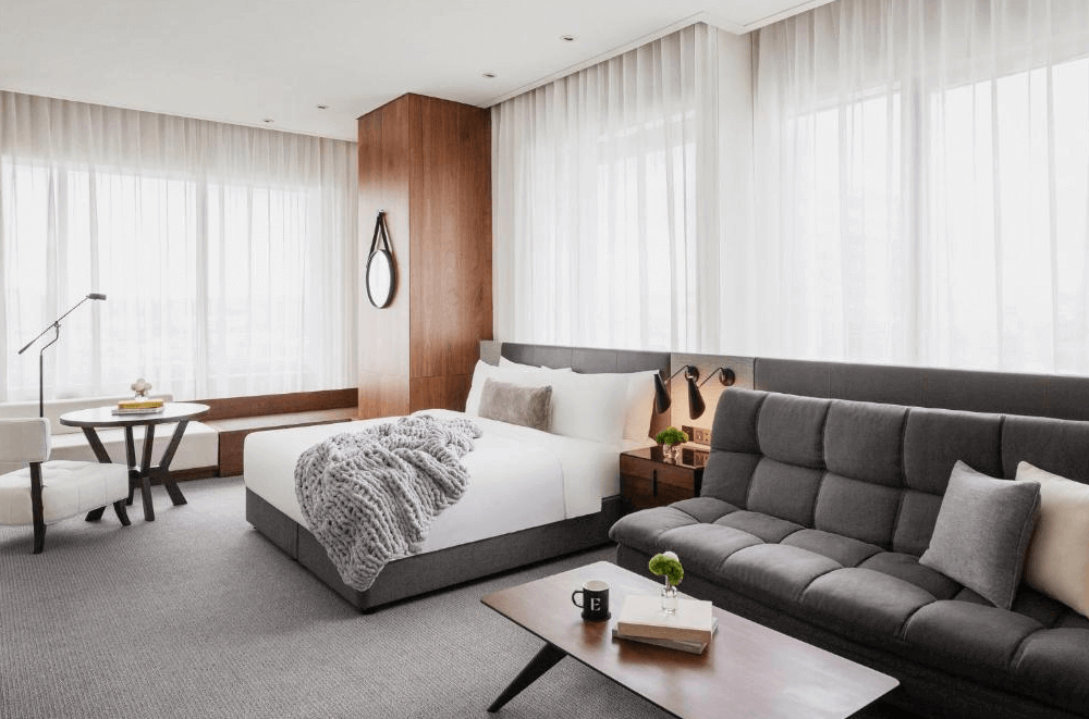 【新竹東區住宿】新竹伊普索飯店現代簡約風格客房，設有柔和白紗落地窗、大床與灰色沙發，整體設計溫暖雅緻，營造舒適居住空間。