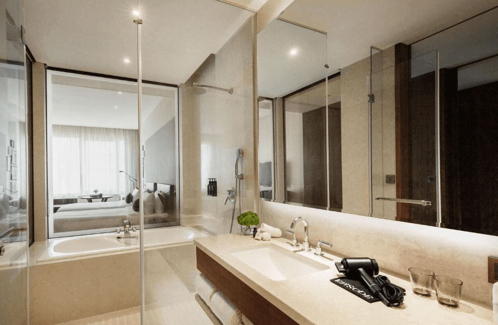 【新竹東區住宿】新竹伊普索飯店浴室空間，設有大片鏡面與乾濕分離設計，浴缸與房間以透明玻璃相隔，整體設計現代高雅。