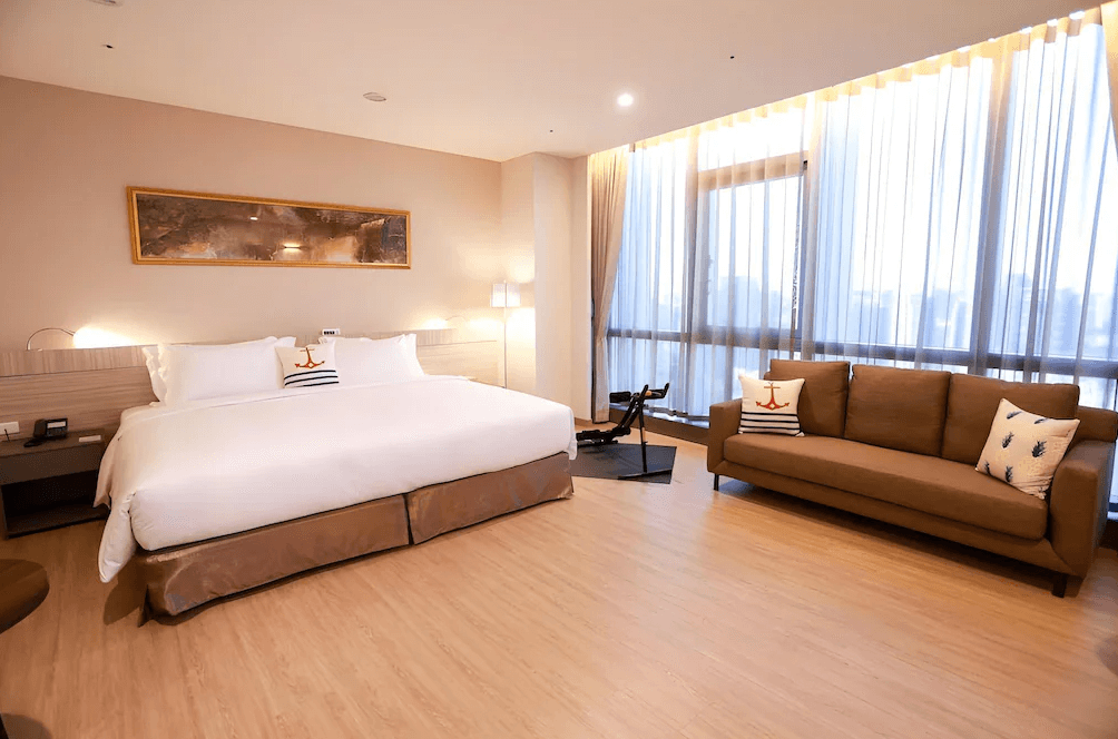 【竹北住宿】"竹北住宿精選示意圖˙"新竹安捷國際酒店高樓層景觀客房，設有一張加大雙人床與沙發休憩區，大片落地窗引進自然光，空間明亮舒適。