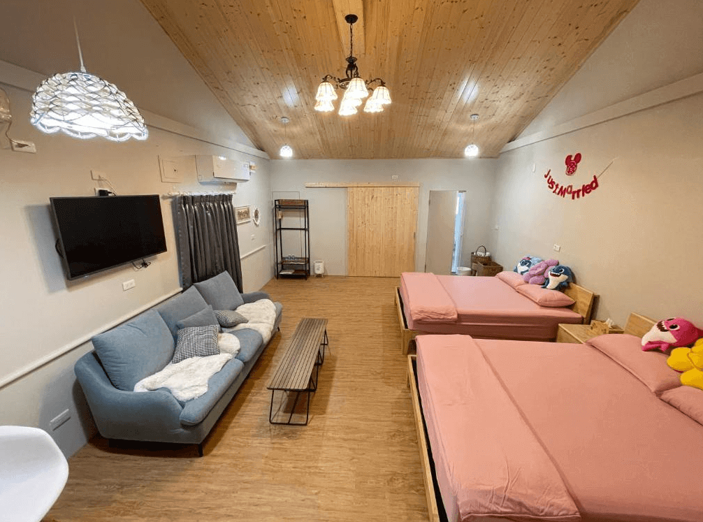 【西螺住宿】旅人路過時家庭房空間寬敞，配有兩張雙人床與大型沙發區，天花板為原木材質，布置以溫馨燈飾與可愛玩偶點綴。