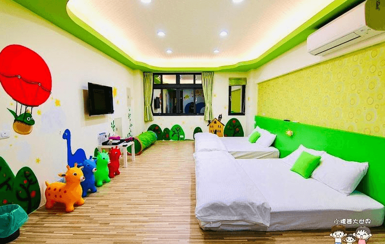 【竹山住宿】晚安熊親子民宿綠色童趣房型，房內設有兩張雙人床、牆面繪有熱氣球與可愛動物圖案，搭配跳跳馬玩具與綠色軟墊地景裝飾，營造充滿童心的遊戲空間。