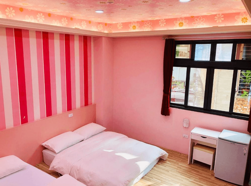 【竹山住宿】晚安熊親子民宿粉嫩公主風格房型，牆面為粉紅與紅色條紋設計，配有兩張雙人床、小書桌與冰箱，空間明亮溫馨，適合家庭或女孩入住。