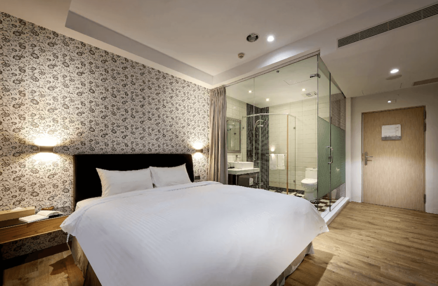 【清水住宿】梧棲行旅現代雙人房，簡約設計搭配開放式玻璃衛浴，房內為白色床鋪與木質地板，營造舒適氛圍。