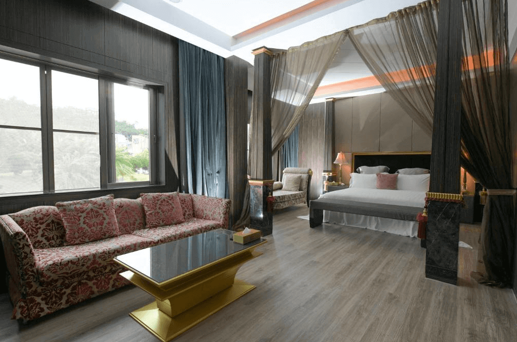 【新竹東區住宿】湖山風景旅館奢華主題房，配有四柱床與簾帳設計，搭配古典風沙發與金色茶几，營造出高貴典雅的住宿氛圍。