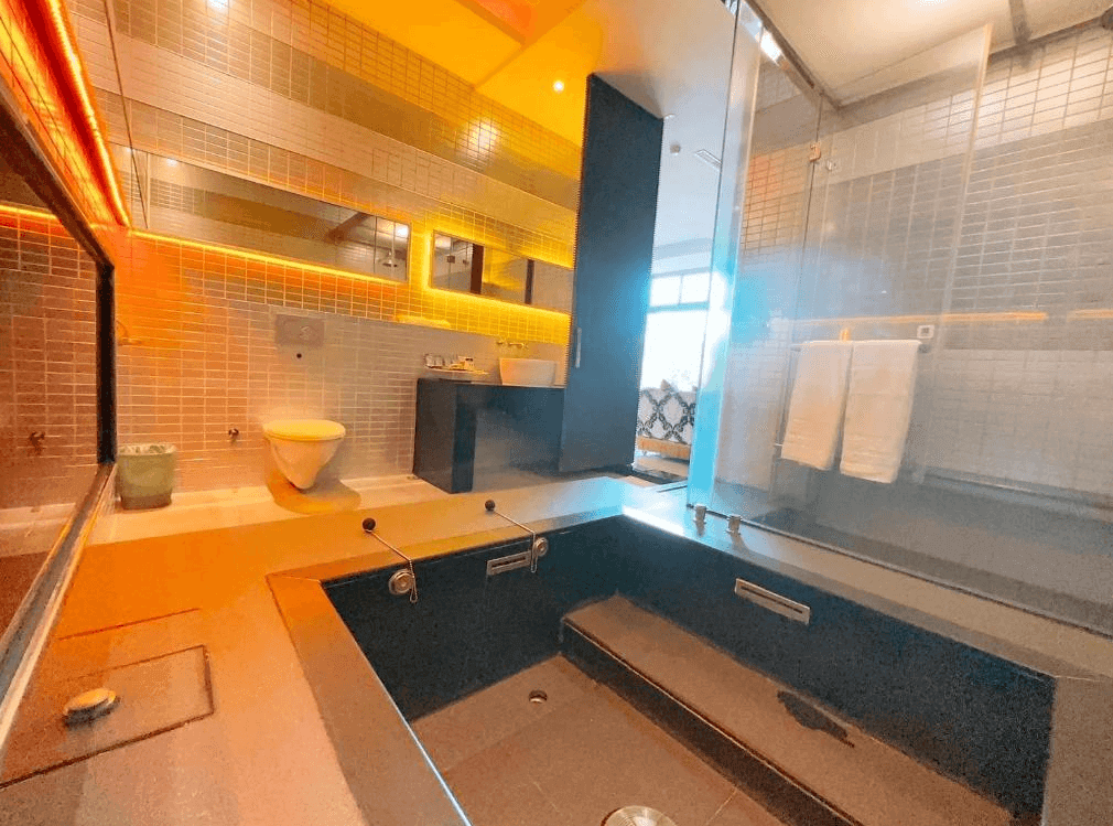 【新竹東區住宿】湖山風景旅館寬敞浴室，設有深浴池、乾濕分離空間與黃光氛圍燈，牆面以馬賽克磚裝飾，營造溫泉般療癒體驗。