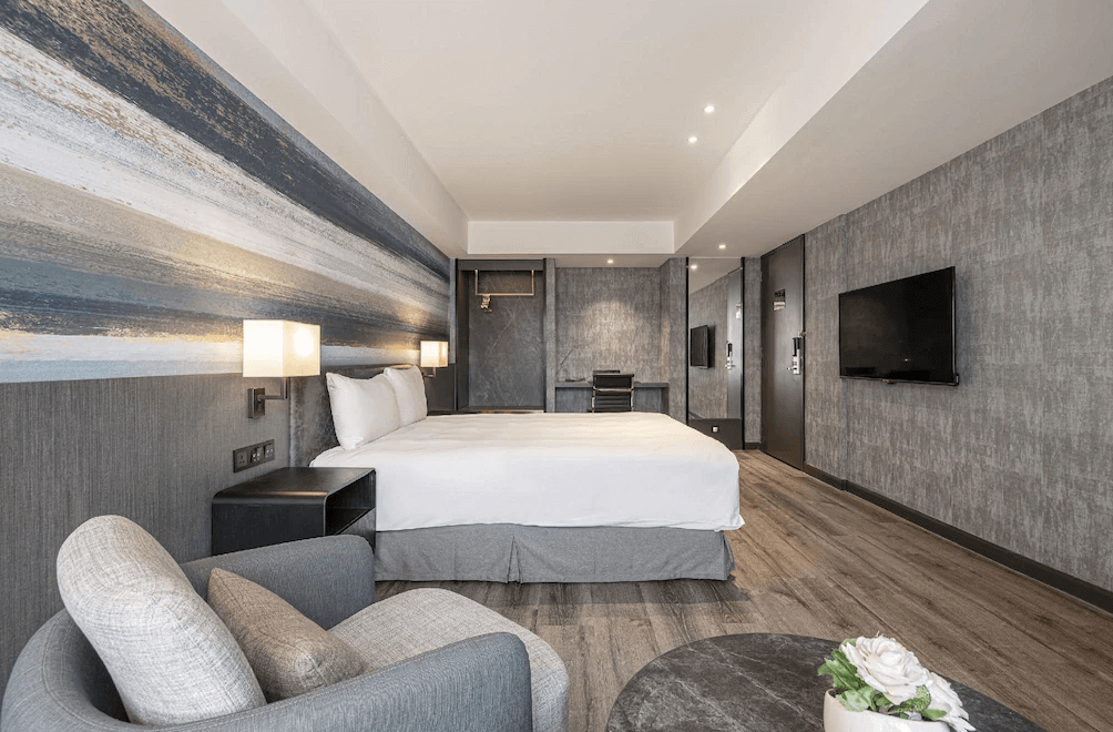 【新竹東區住宿】煙波大飯店－都會館大床房，牆面採漸層藝術設計，室內備有沙發椅、書桌與壁掛電視，空間感十足。