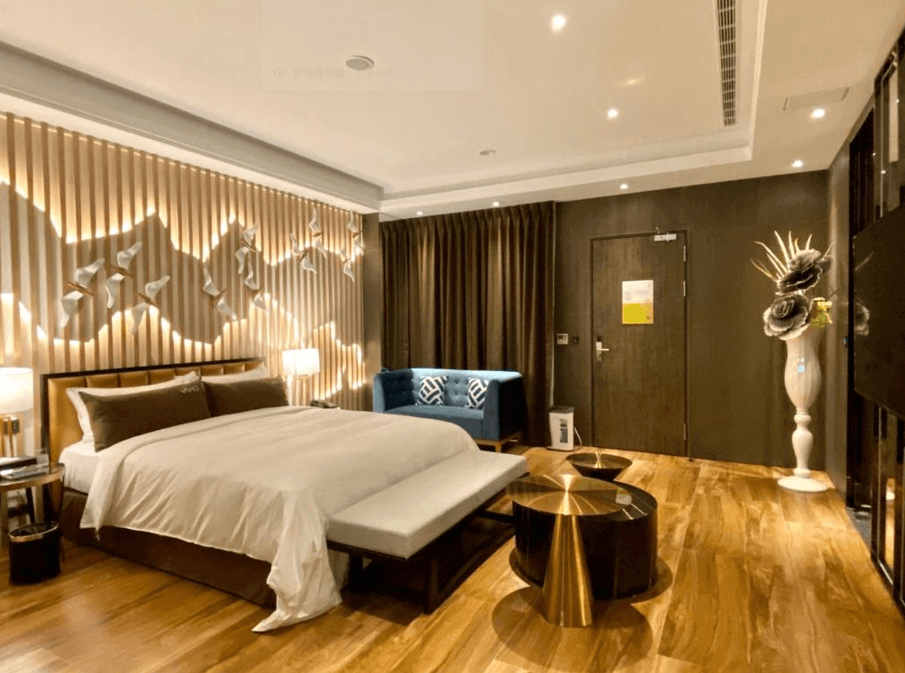 【新竹東區住宿】琺何精品旅館豪華雙人房，設計現代時尚，牆面燈光雕塑與木地板相互呼應，搭配藍色沙發與藝術花瓶，展現獨特品味。