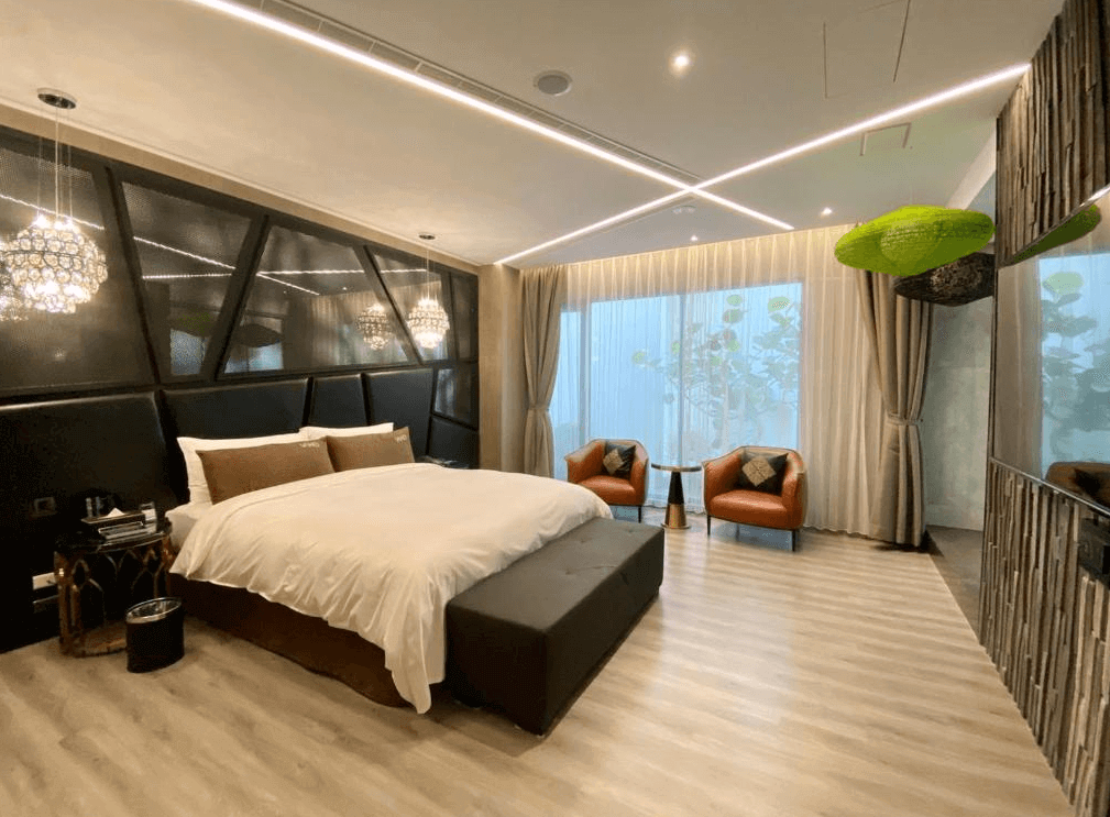 【新竹東區住宿】琺何精品旅館主題套房，黑色幾何牆面搭配水晶吊燈與自然採光，房內設有皮椅與窗邊休憩區，氛圍高雅舒適。